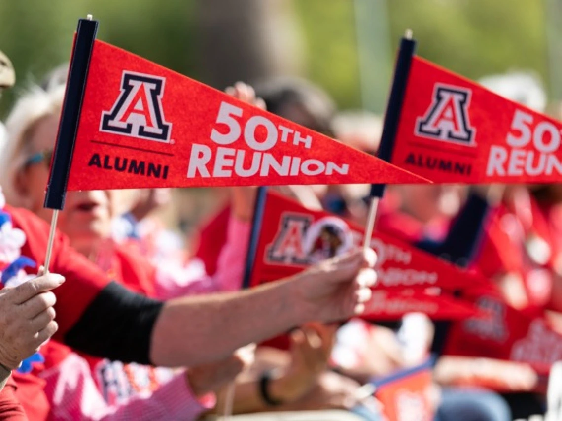 Hands holding red and white flags that read "Alumni 50th Reunion"