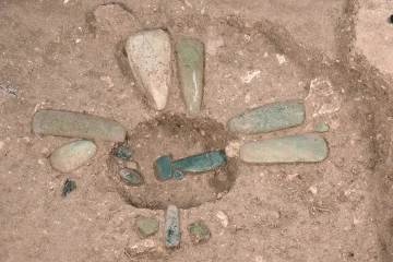 Jade ritual axes and ornaments uncovered from a filled ceremonial pit.